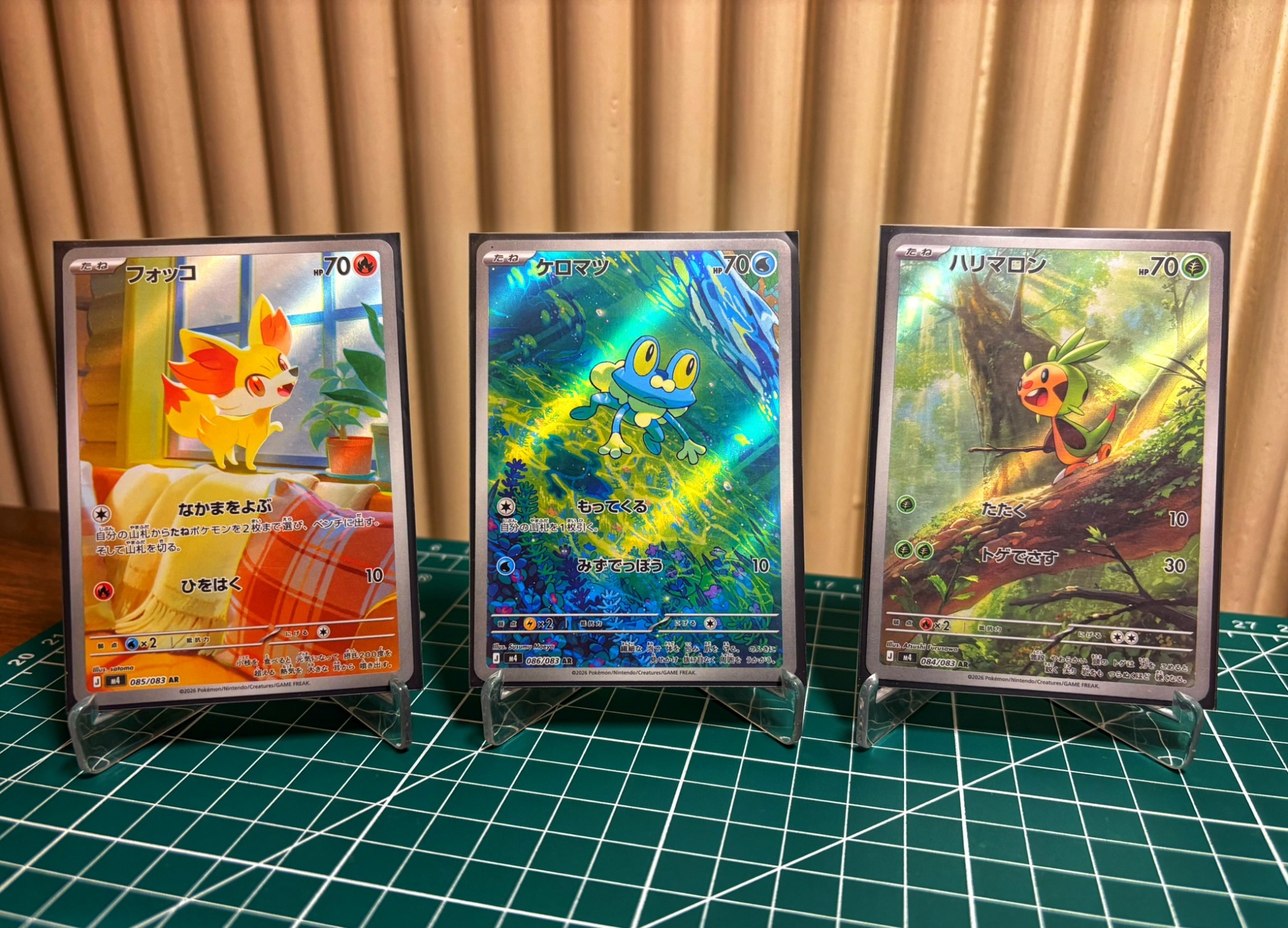 Three graded Pokémon cards displayed on stands