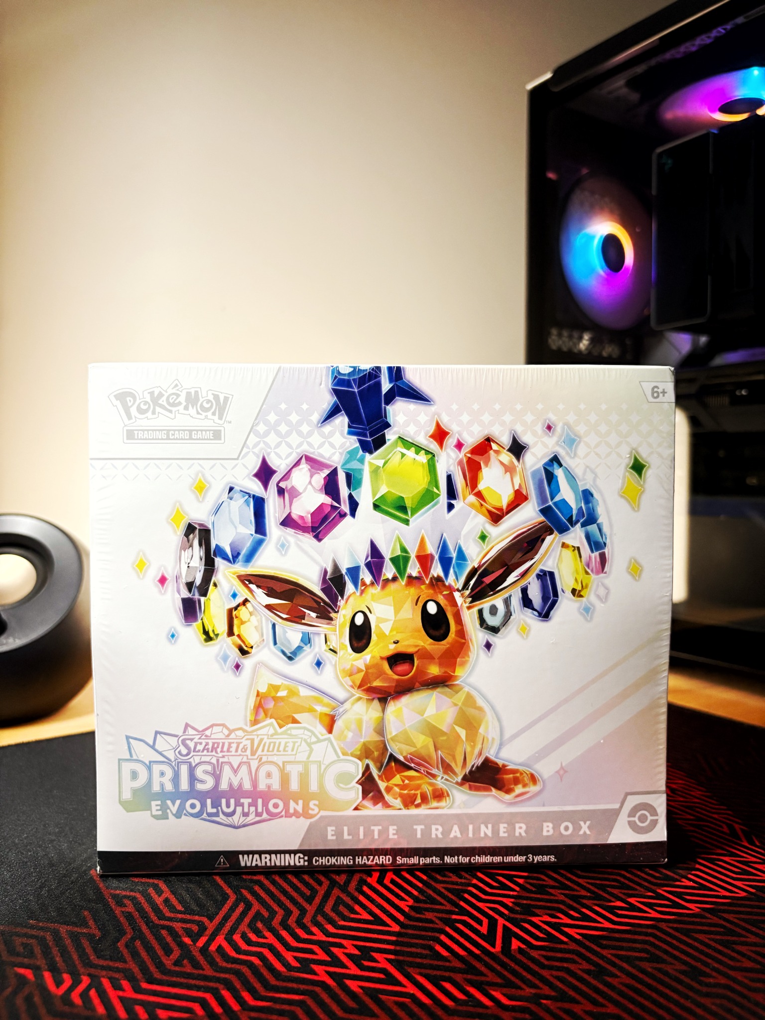 A Pokémon Prismatic Evolutions collection box displayed on a shelf